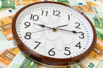 Clock and Euro currency banknotes. Time is money concept