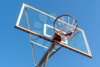 Basketball ring and board with white net. Low angle view. Sunny day. Clear sky.