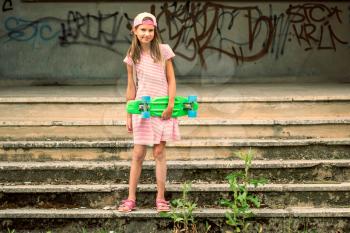 Girl child with skateboard at abandoned building