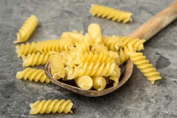 Uncooked pasta in wooden spoon closeup