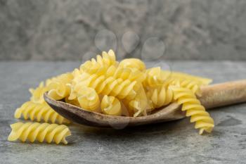 Uncooked macaroni in wooden spoon close-up