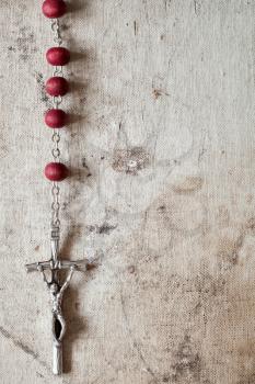  Catholic rosary hanging on old canvas background. Copy-space.
