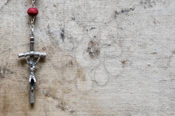 Christian rosary hanging on old canvas background. Copy-space.