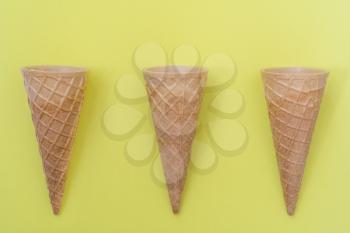 Three sweet wafer cones on yellow background