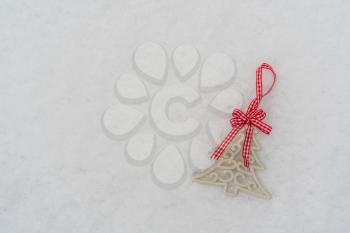 Decoration shaped as Christmas tree lying on the white snow,  top view, copy space