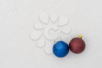 Blue and red Christmas baubles on the snow. Top view, copy-space.