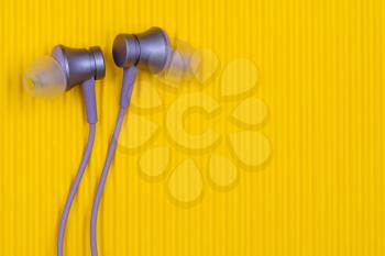 Purple audio earphones on the yellow background. Copy space.