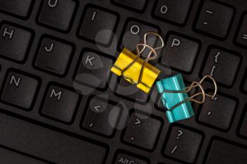 Color paper clips on the black computer keyboard