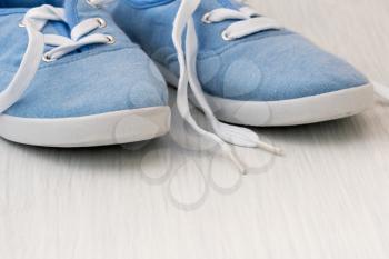 Blue canvas shoes on the white wooden surface
