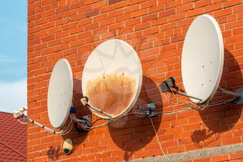 Three Satellite dishes on the brick wall