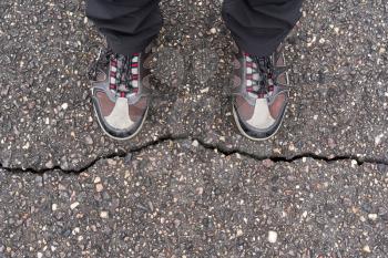 A confused man having a dilemma, standing against crack on a road. Dilemmas concept.