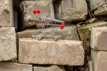 Shopping cart on the pile of old bricks. Concept for renovation expenses.