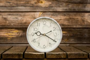 Classic wall clock on the weathered wooden background