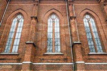 Old huge neogothic building wall. Tall windows. Brickwork.