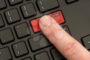 Finger pressing the ENTER button of computer keyboard