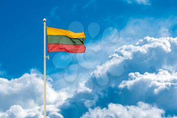 Lithuanian national flag waving on wind against blue cloudy sky