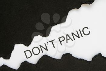 Top view of black torn paper and the text DON'T PANIC on a white background. 