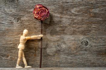 Wooden man holding dried rose, copy-space