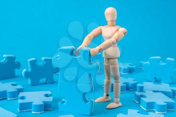 Wooden man assembling jigsaw puzzle. Business concept for growth success process