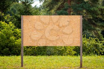 Wooden blank billboard with empty space in a park on a sunny day