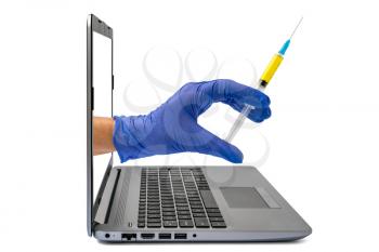 A hand holds a syringe, outstretched through the laptop screen on a white background. Online medicine concept, medical technology, stay home.