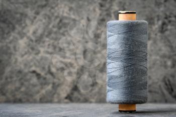 Spool of grey thread on a stone background. Copy space.
