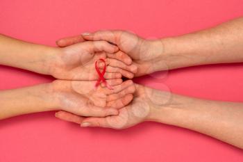 Adult and child hands holding pink ribbon. Breast cancer awareness, abdominal cancer awareness and October Pink day background , world cancer day.