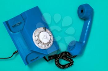 Old blue telephone rings with handset off