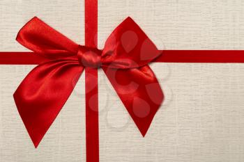 Red bow on gift box background, close-up. Decorative gift box with ribbon.