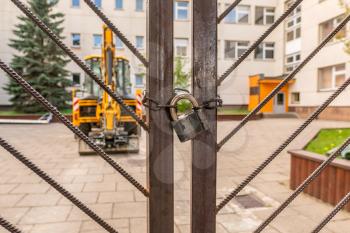 Metal gates with padlock of industrial yard with parked tractor