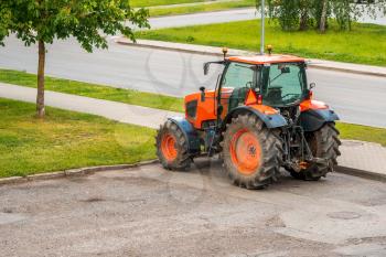 Red tractor on the city empty parking lot