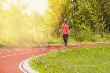 Girl running during sunny morning on school stadium track