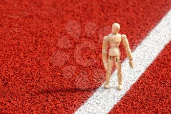 Wooden man doing exercises on running track with rubber surface