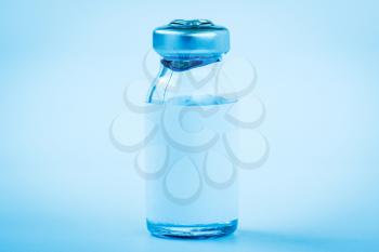 Close up of medical bottle with vaccine. Blue toned image.