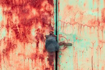 Close up of padlock and old metal hasp and staple on an rusty metal door