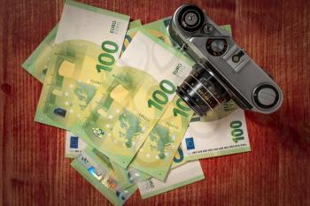 Making money on photography. Photographer's income. Old film camera and pile of money
