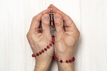 Hands folded in prayer with a Christian rosary with a cross 