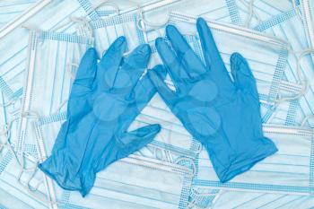 A pair of thin blue medical latex gloves and a lot of medical face mask. Disposable rubber medical gloves and mask. Protective subjects. 