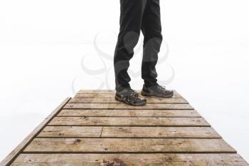 Man standing on a wooden bridge in the fog. Foggy morning by the lakeside during winter.