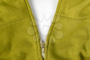 Unzipped zipper on a green sweater with a white copy space. Close up.