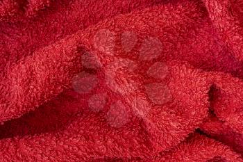 Undulating plush bath towel fabric. Red fabric and texture concept - close up of a towel terry cloth or terry textile background
