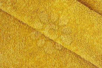 Yellow plush bath towel fabric. Yellow fabric and texture concept - close up of a towel terry cloth or terry textile background