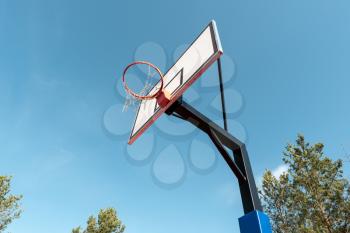 Broken metal net on basketball basket outside on blue sky background