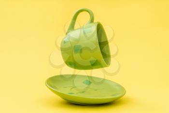 Empty green cup with plate floating on the yellow background