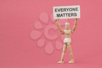 Wooden man holding a card with text EVERYONE MATTERS . Equality and diversity concept.