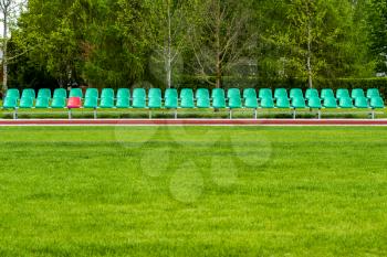 Empty chairs for spare team/ spare persons on the soccer field with green grass