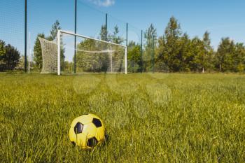 Ball on soccer field with football goals on background