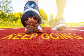 Athlete runner feet and message KEEP GOING on a  on a running track