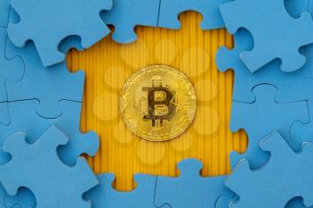 Jigsaw puzzle with golden bitcoin underneath. Virtual currency,  cryptocurrency concept.