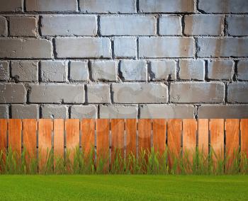 Green grass in garden with fence near the brick wall